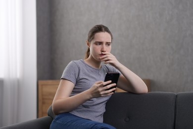 Photo of Depressed woman calling hotline for mental health help on sofa at home