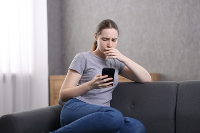 Photo of Depressed woman calling hotline for mental health help on sofa at home