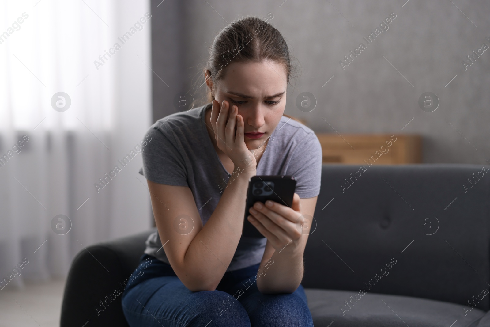 Photo of Depressed woman calling hotline for mental health help on sofa at home