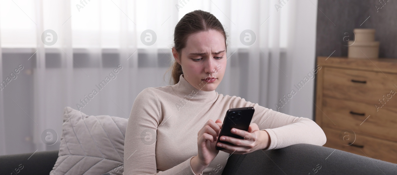 Photo of Depressed woman calling hotline for mental health help on sofa at home