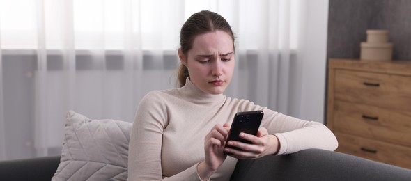 Photo of Depressed woman calling hotline for mental health help on sofa at home