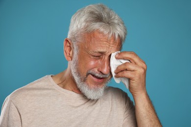 Photo of Sad senior man crying on light blue background