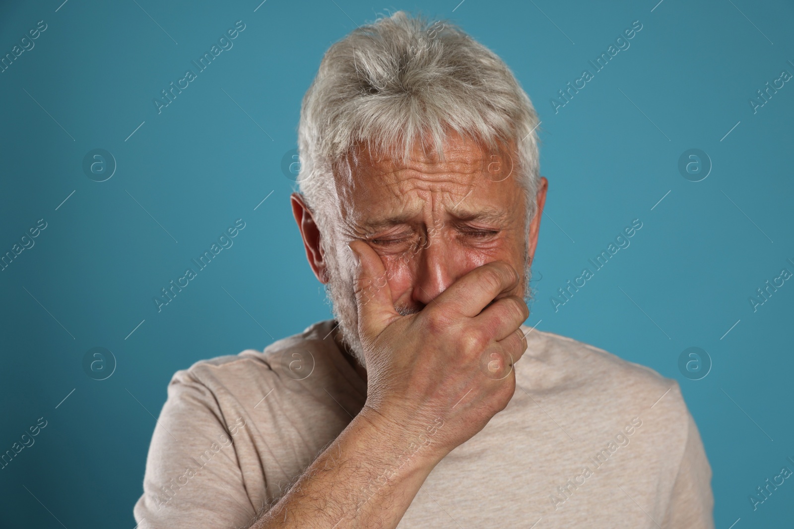 Photo of Sad senior man crying on light blue background