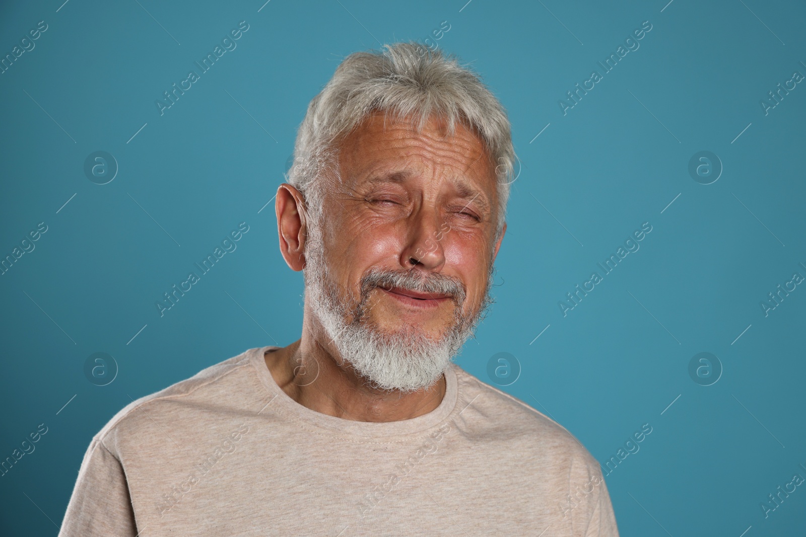 Photo of Sad senior man crying on light blue background