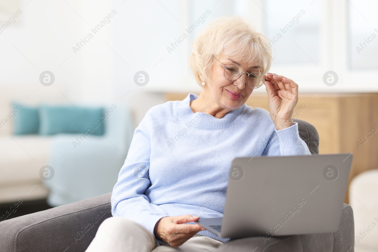 Photo of Portrait of beautiful grandmother using laptop at home