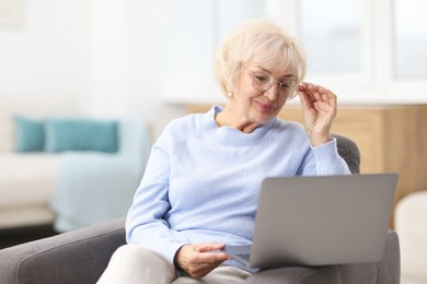 Photo of Portrait of beautiful grandmother using laptop at home