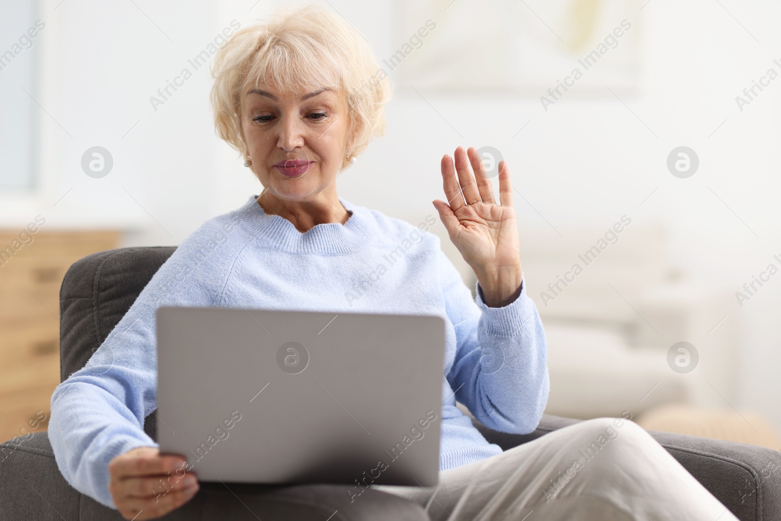 Photo of Beautiful grandmother having video chat via laptop at home