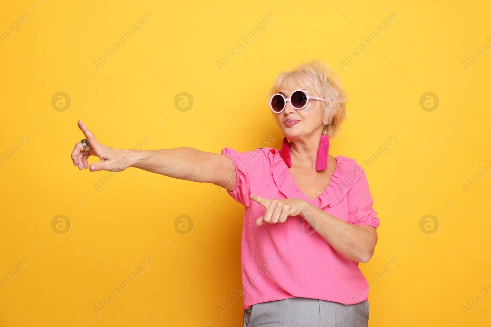 Photo of Portrait of cool grandmother in sunglasses on orange background