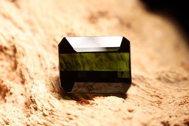 Photo of Beautiful shiny green gemstone on stone, closeup