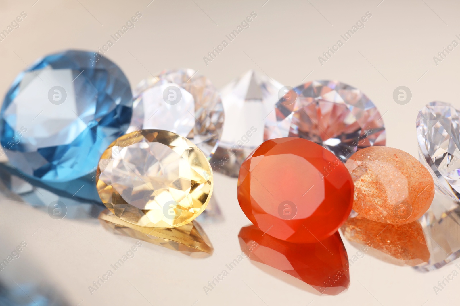 Photo of Beautiful shiny colorful gemstones on light background, closeup