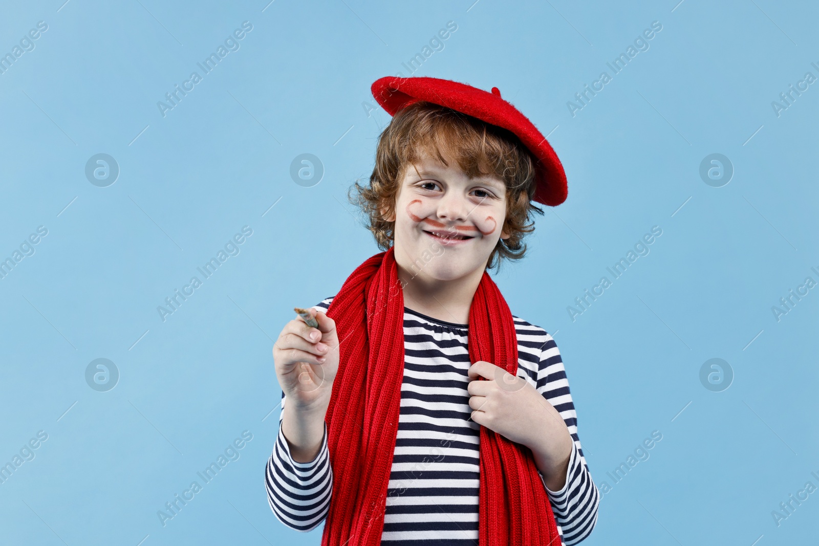 Photo of Smiling boy in mime costume with brush on light blue background. Surprise party