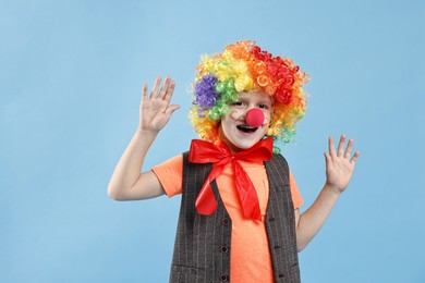 Photo of Happy boy dressed like clown on light blue background. Surprise party