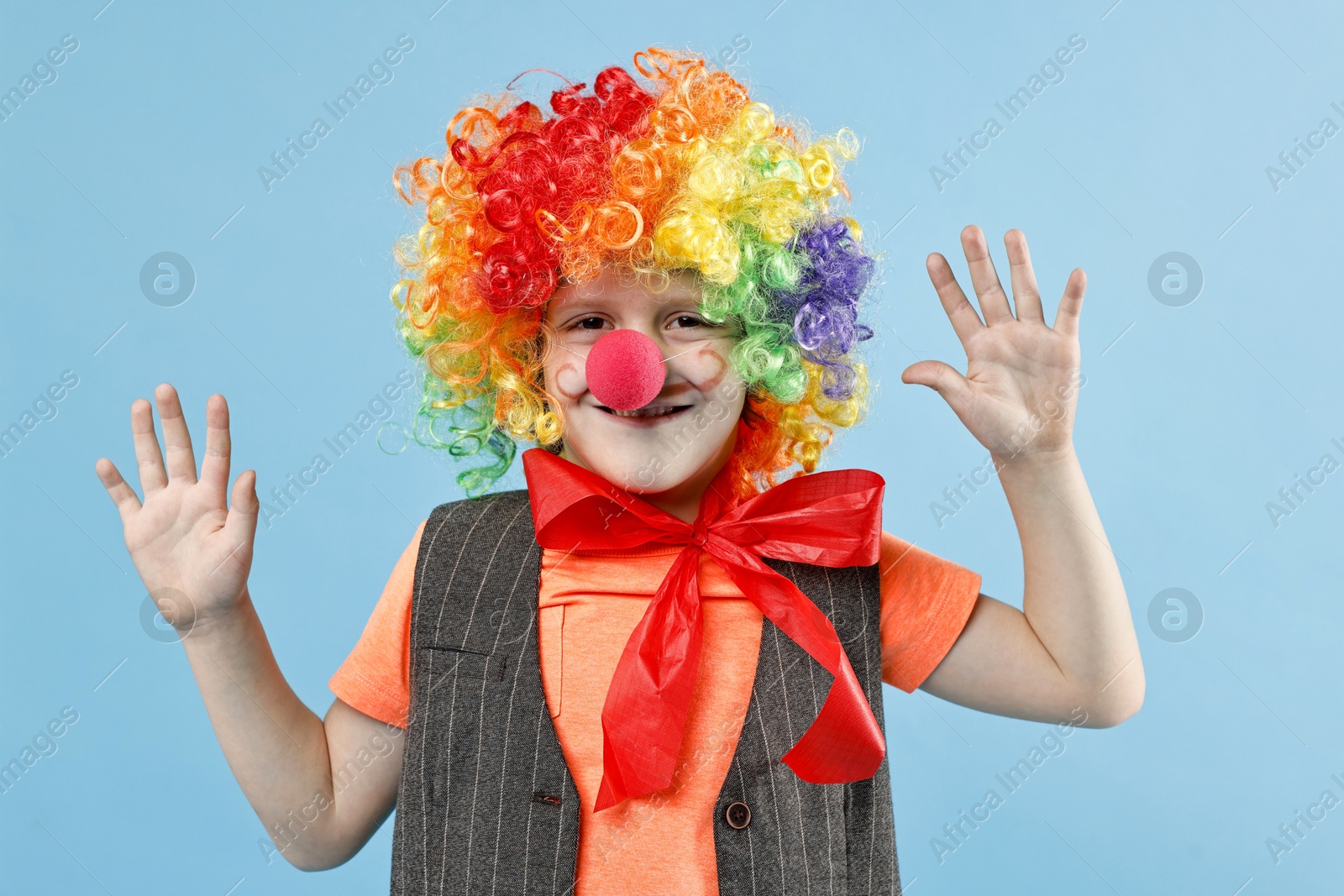 Photo of Happy boy dressed like clown on light blue background. Surprise party