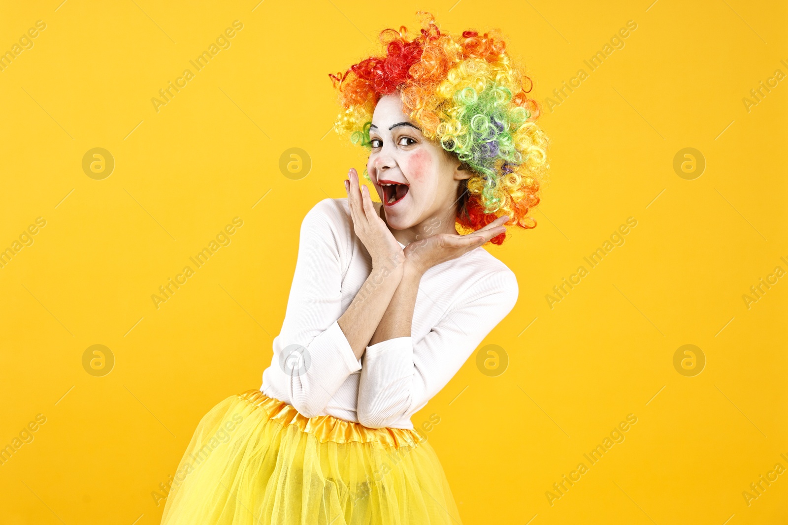 Photo of Happy girl dressed like clown on yellow background. Surprise party