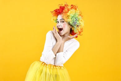 Photo of Happy girl dressed like clown on yellow background. Surprise party