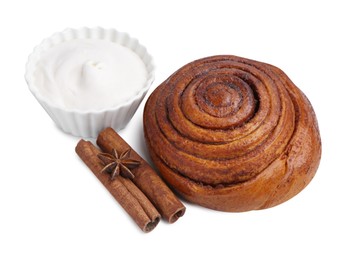 Photo of Tasty cinnamon roll with cream and sticks isolated on white