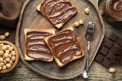 Photo of Tasty sandwiches with chocolate butter and hazelnuts on wooden table, flat lay