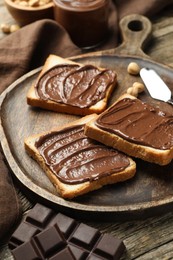 Photo of Tasty sandwiches with chocolate butter and pieces of chocolate on table, closeup