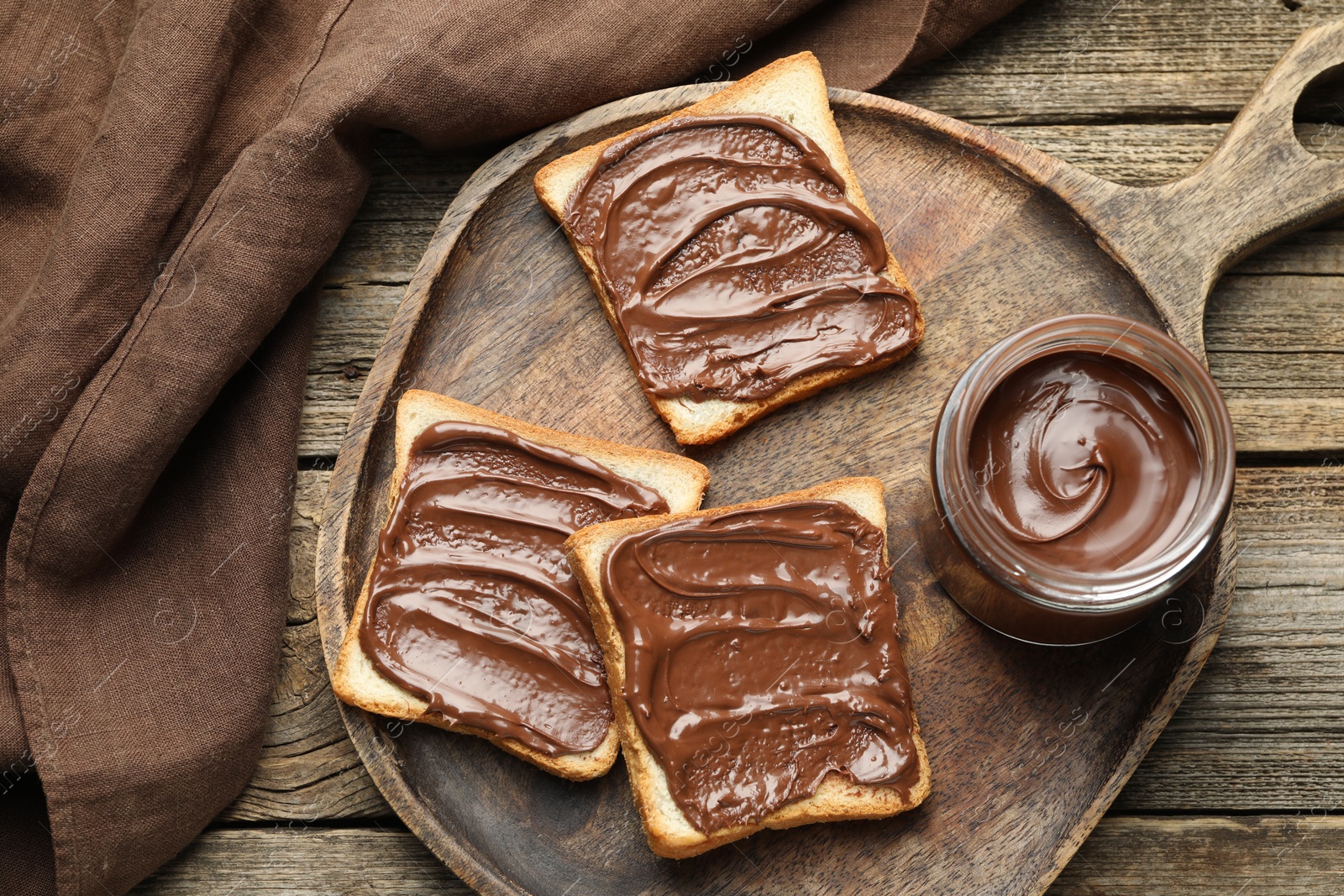 Photo of Tasty sandwiches with chocolate butter on wooden table, top view