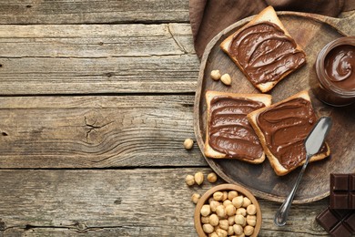 Photo of Tasty sandwiches with chocolate butter and hazelnuts on wooden table, flat lay. Space for text