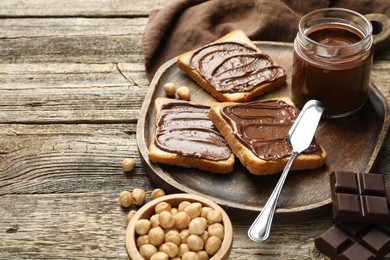 Photo of Tasty sandwiches with chocolate butter and hazelnuts on wooden table, closeup. Space for text