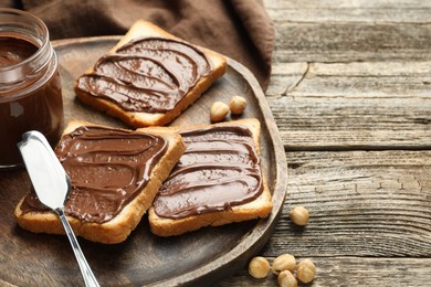 Tasty sandwiches with chocolate butter and hazelnuts on wooden table, closeup. Space for text