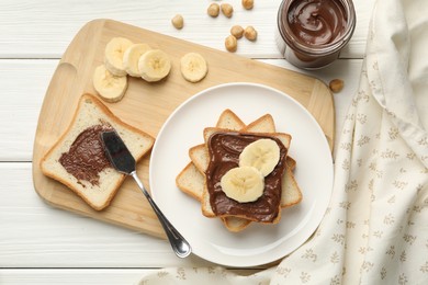 Photo of Sandwiches with chocolate butter, bananas and hazelnuts on white wooden table, flat lay