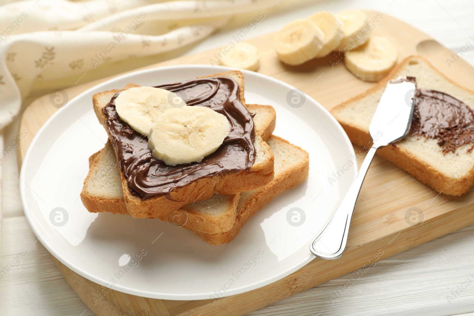 Photo of Sandwiches with chocolate butter and banana on white wooden table, closeup