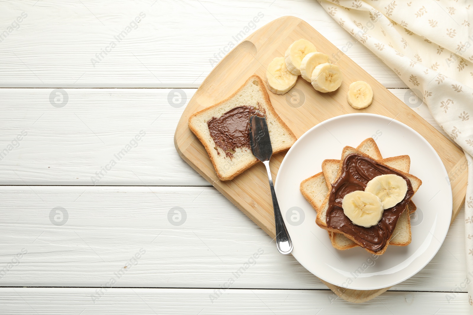 Photo of Sandwiches with chocolate butter and banana on white wooden table, top view. Space for text