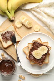 Photo of Sandwiches with chocolate butter, bananas and hazelnuts on white wooden table, flat lay