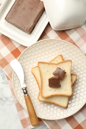 Photo of Sandwiches with chocolate butter and knife on white marble table, flat lay