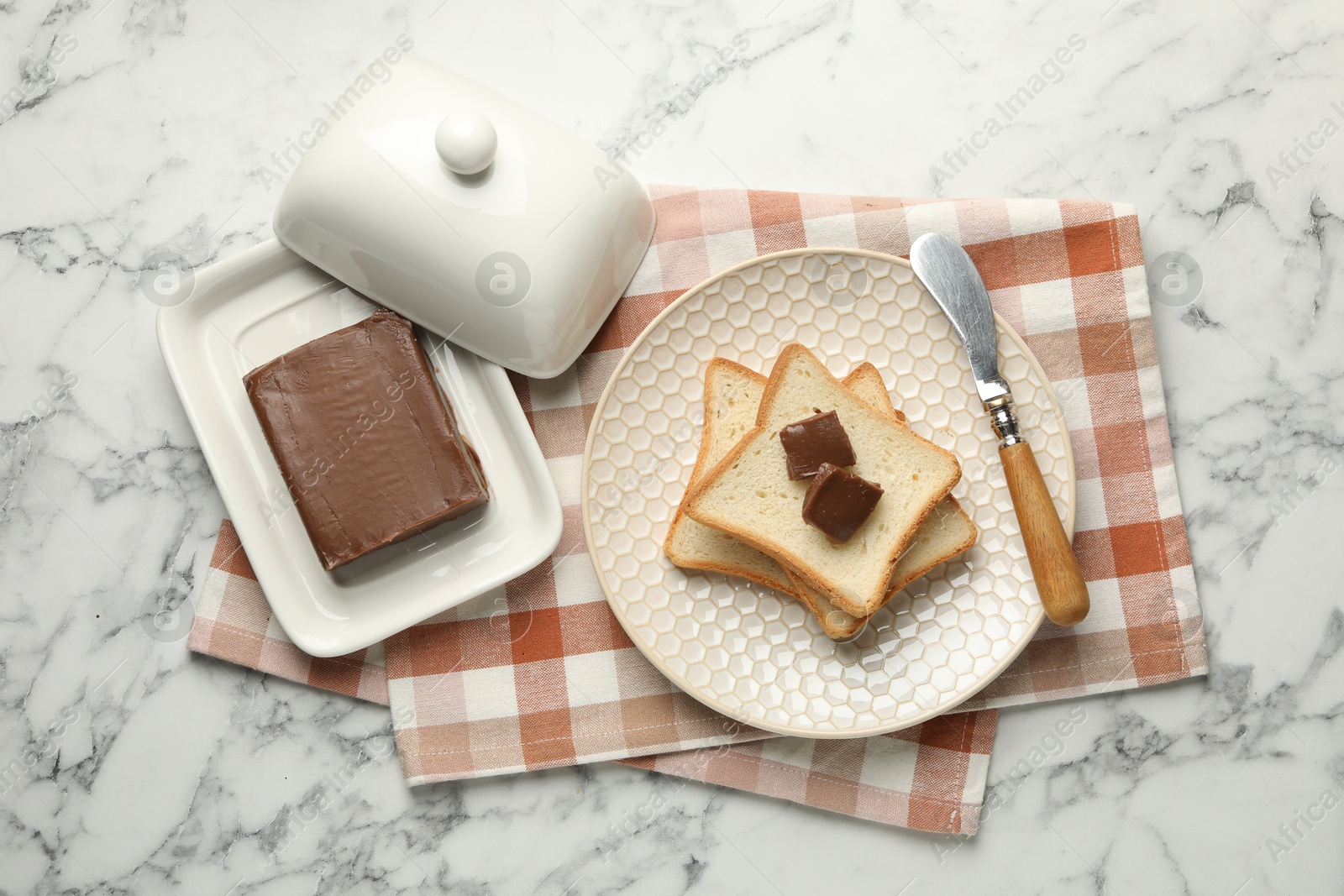 Photo of Sandwiches with chocolate butter and knife on white marble table, flat lay