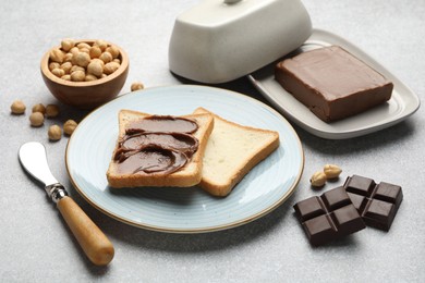 Photo of Sandwiches with chocolate butter, hazelnuts and knife on grey table, closeup