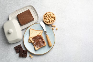 Photo of Sandwiches with chocolate butter, hazelnuts and knife on grey table, flat lay. Space for text