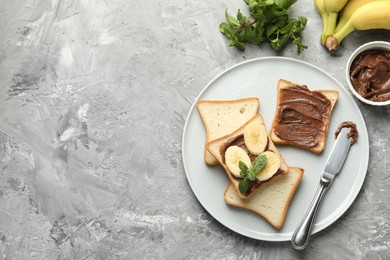 Photo of Sandwiches with chocolate butter, bananas, mint and knife on grey table, flat lay. Space for text