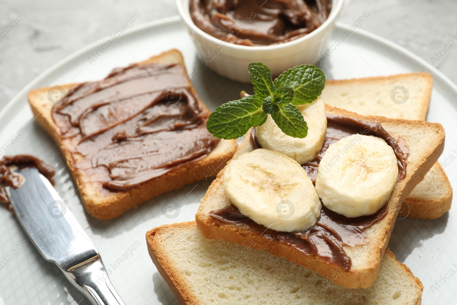 Photo of Sandwiches with chocolate butter, banana, mint and knife on table, closeup