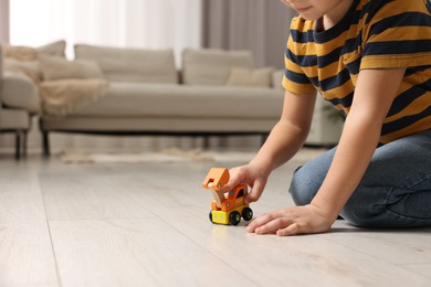 Photo of Little boy playing with toy car at home, closeup. Space for text