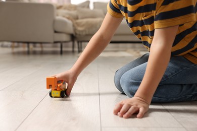 Photo of Little boy playing with toy car at home, closeup