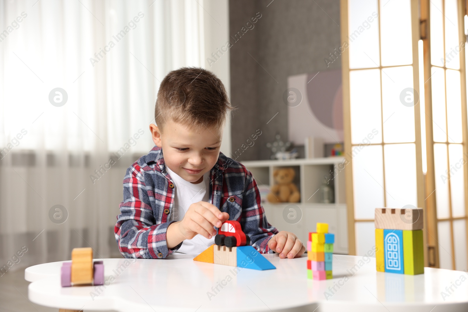 Photo of Little boy playing with toys at table indoors