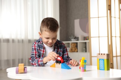 Photo of Little boy playing with toys at table indoors