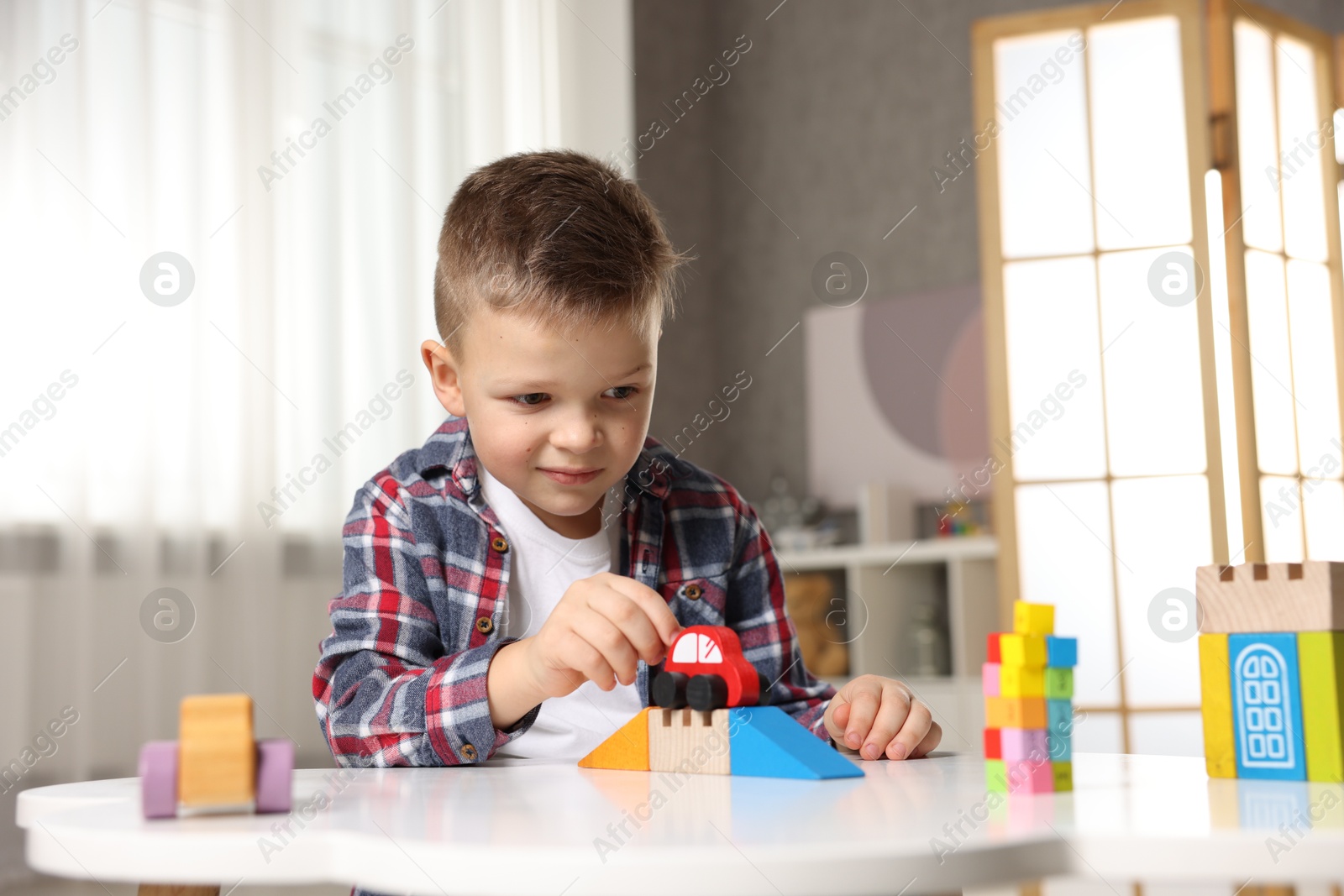 Photo of Little boy playing with toys at table indoors