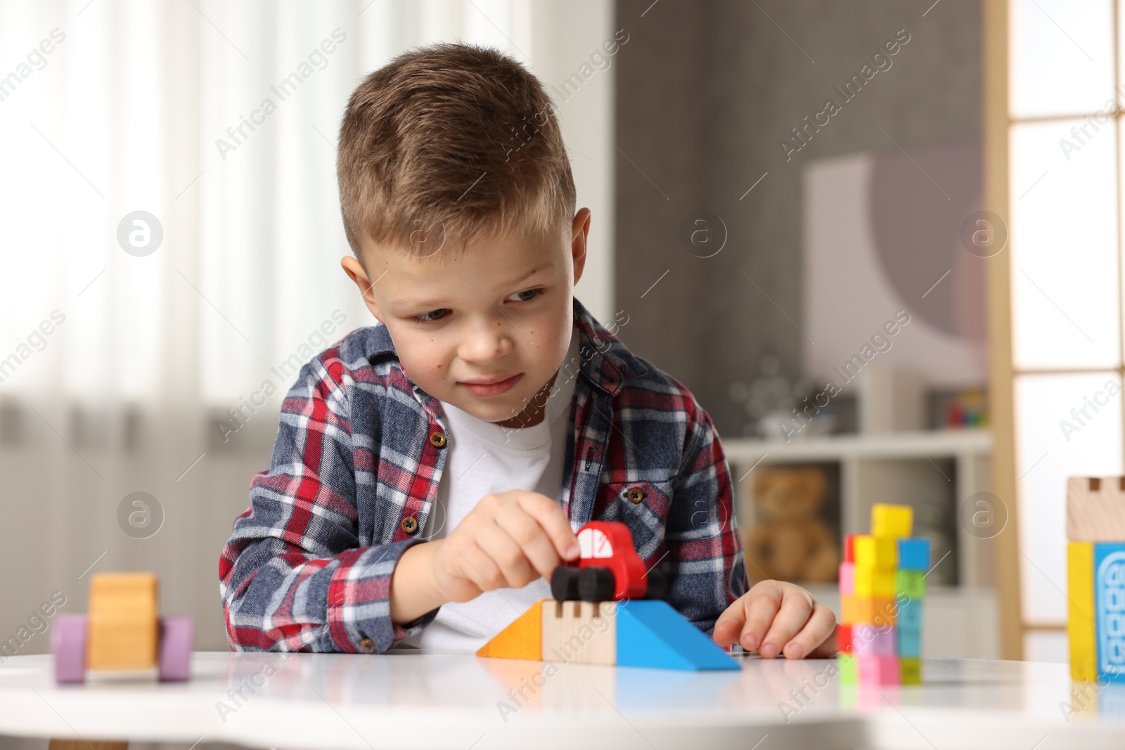 Photo of Little boy playing with toys at table indoors