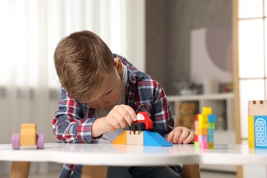 Photo of Little boy playing with toys at table indoors