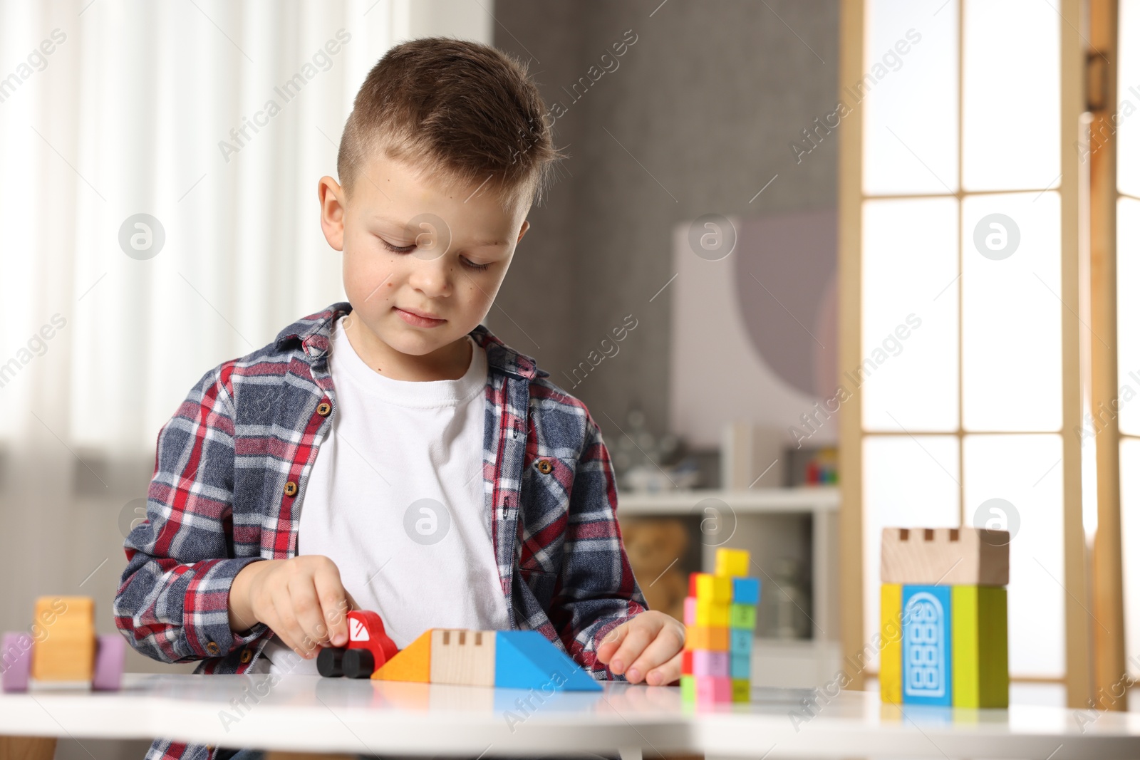 Photo of Little boy playing with toys at table indoors