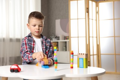 Photo of Little boy playing with toys at table indoors