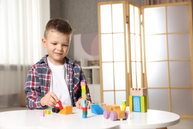 Photo of Little boy playing with toys at table indoors