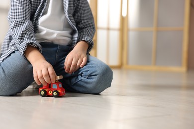 Photo of Little boy playing with toy car at home, closeup. Space for text