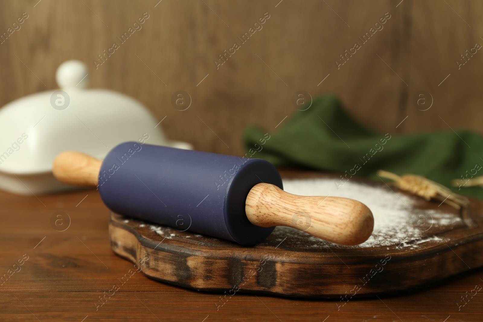 Photo of Rolling pin, board and flour on wooden table, closeup