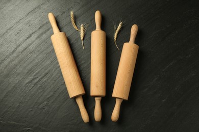 Photo of Wooden rolling pins and spikes on dark gray textured table, flat lay