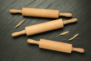 Photo of Wooden rolling pins and spikes on dark gray textured table, flat lay